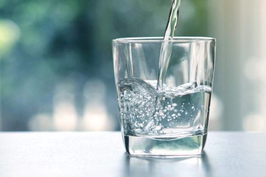 Close up the  pouring purified fresh drink water from the bottle on table in living room